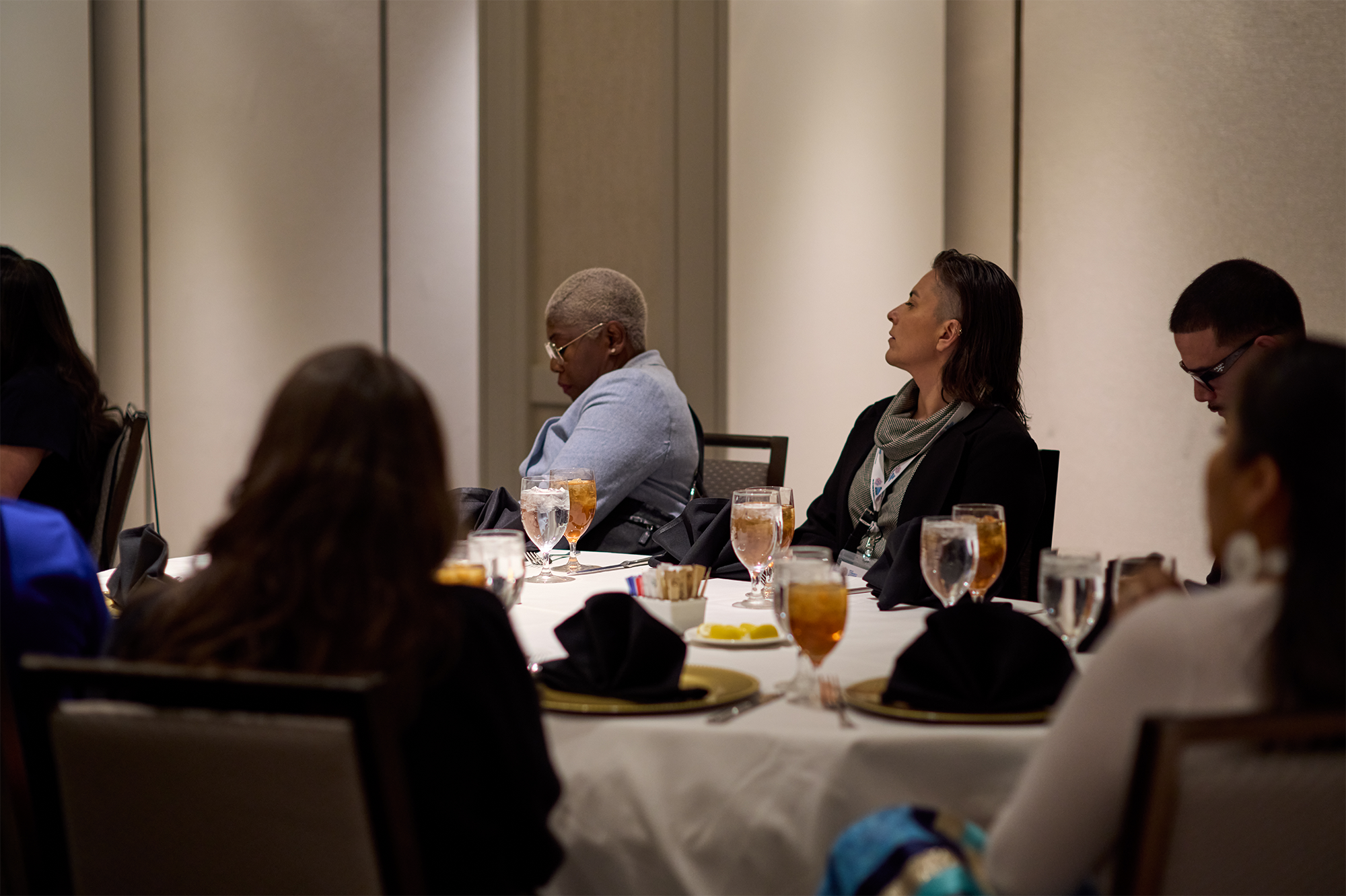 Six people seated around a table and looking to the left side of the room.